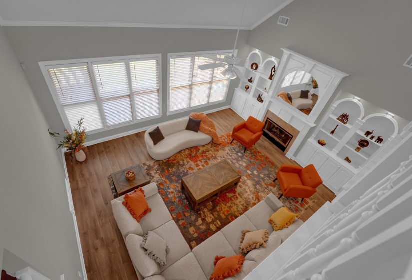 Living room featuring a fireplace, ceiling fan, wood-type flooring, and ornamental molding
