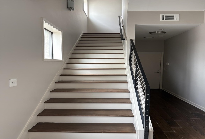 Stairway with wood finished floors, storage closet, and first floor access to garage