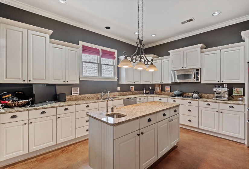 Kitchen featuring white shaker-style cabinetry, granite countertops, and an integrated stainless steel microwave