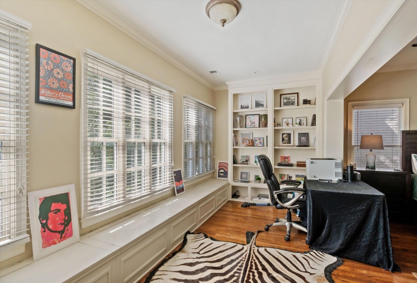 Built-in shelving and window seating featuring wood-finish flooring, crown molding, and multiple windows