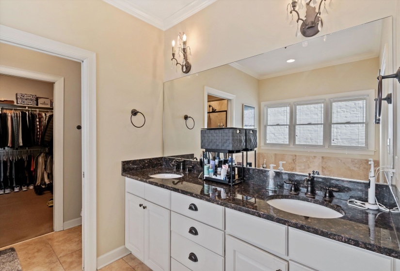 Double vanity with dark stone countertop, undermount sinks, and white cabinetry