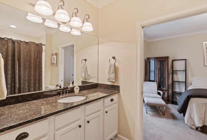 Bathroom vanity featuring a single basin sink, dark stone countertop, and white cabinetry with dark hardware