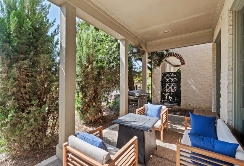 Covered patio featuring a decorative metal gate, brick archway, recessed lighting, and a textured concrete surface