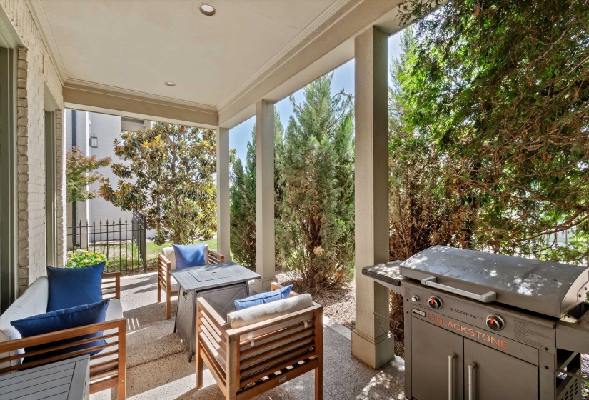 Covered patio featuring recessed lighting, stone flooring, and a privacy hedge
