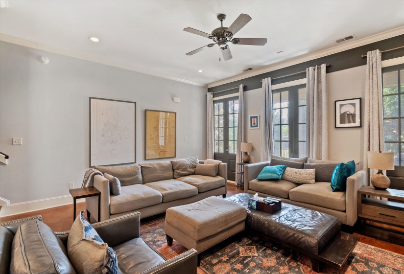 Spacious living area featuring dual French doors, crown molding, recessed lighting, a ceiling fan, and wood-finish flooring