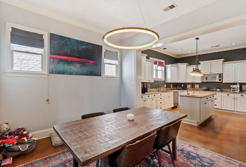 Open-concept dining area and kitchen featuring wood-finish flooring, white cabinetry, a center island, and recessed lighting