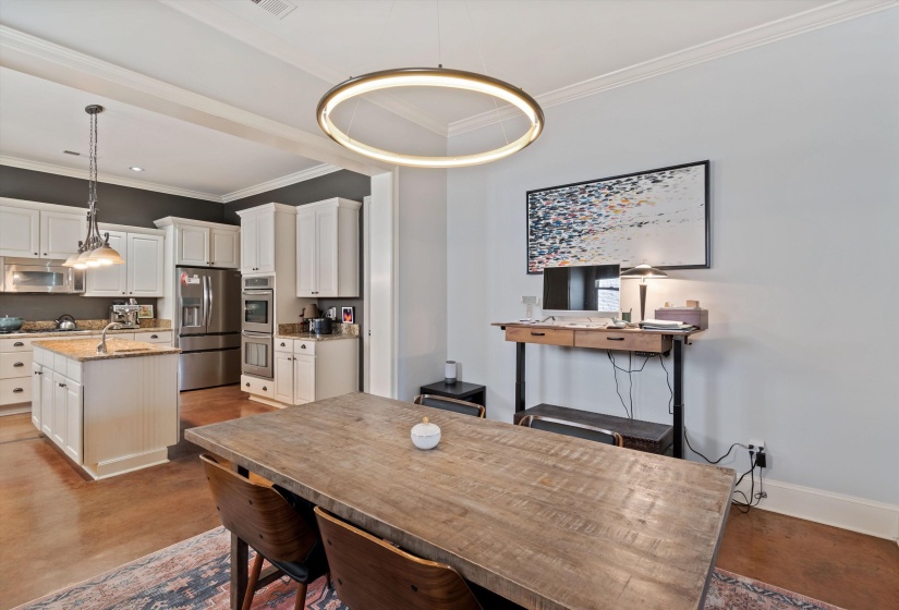 Open-concept dining area featuring a modern circular chandelier, wood-finish flooring, and crown molding