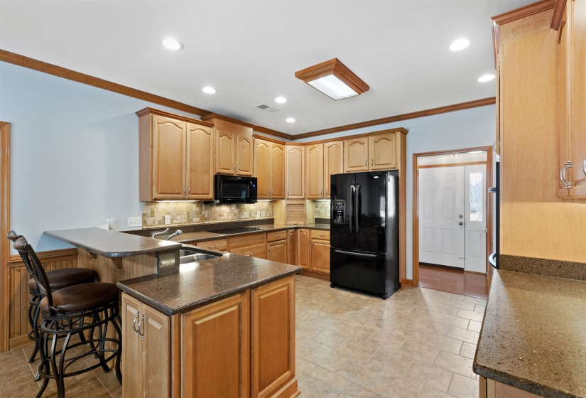 Kitchen featuring light wood cabinetry, stone-finish countertops, and a tiled floor