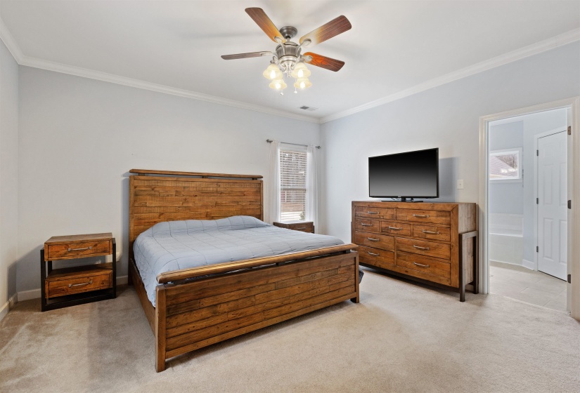 Spacious room featuring light-toned walls, crown molding, a ceiling fan with integrated lighting, and carpeted flooring