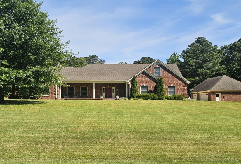 Traditional brick residence featuring a covered front porch, gabled rooflines, and an attached two-car garage
