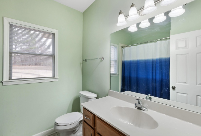 Bathroom featuring a vanity with an integrated sink and chrome faucet, a large wall-mounted mirror, and a window with blinds