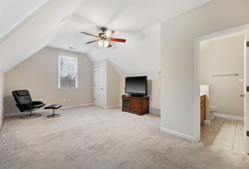 Carpeted bonus room featuring a sloped ceiling, ceiling fan with lighting, and a window with blinds