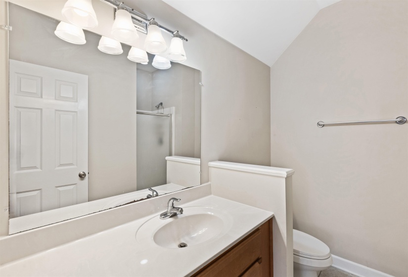 Bathroom vanity featuring a single basin sink, laminate countertop, and wood-finish cabinetry