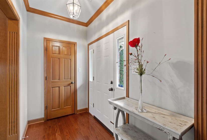 Entryway featuring wood-finish flooring, a six-panel wood door, and a white paneled door with a sidelight