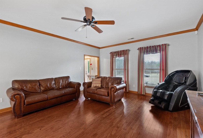 Spacious interior room featuring wood-finish flooring, light-toned walls, and crown molding