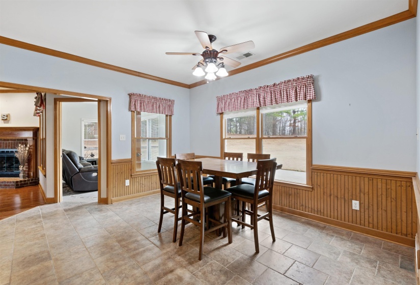 Spacious dining area featuring tile flooring, beadboard wainscoting, and wood trim accents