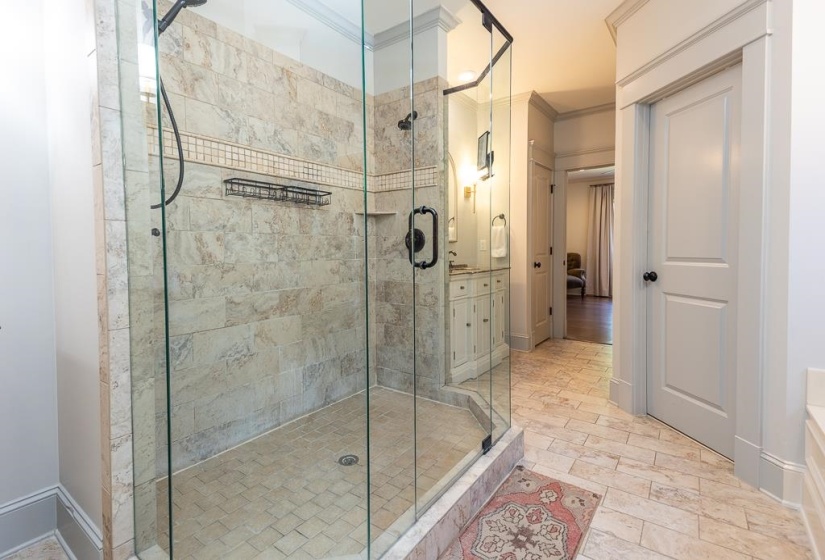 Glass-enclosed shower featuring large format tile walls, a mosaic accent band, and a tiled shower pan