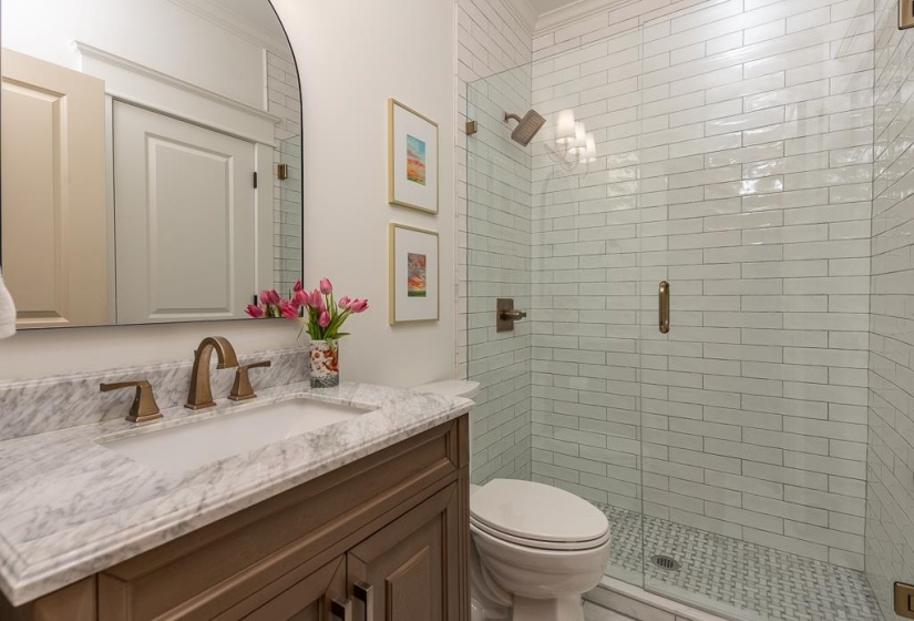 Vanity featuring a built-in sink with a bronze-finish faucet, marble countertop, and wood-finish cabinetry