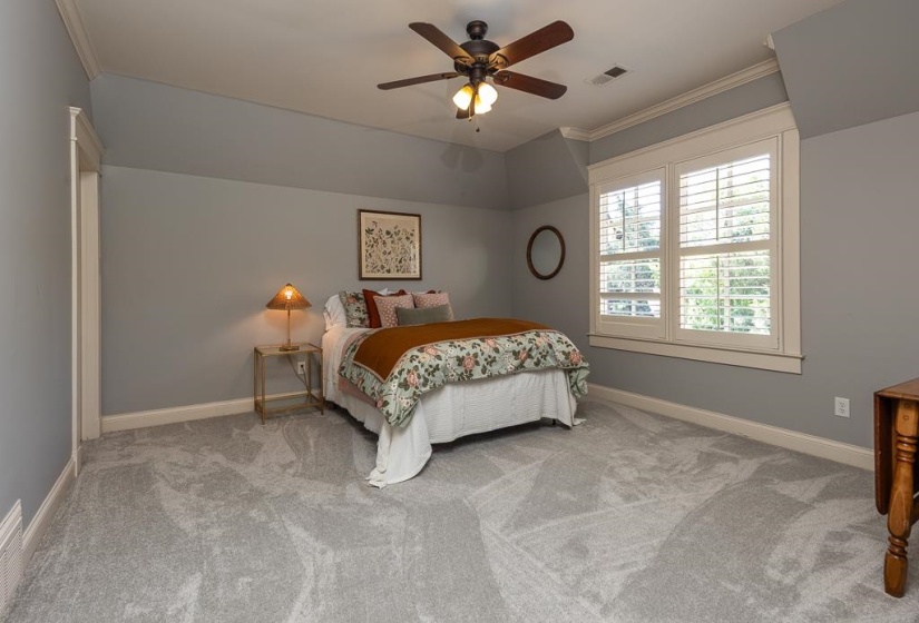 Bedroom featuring sloped ceilings, a ceiling fan, plush gray carpeting, and white window shutters