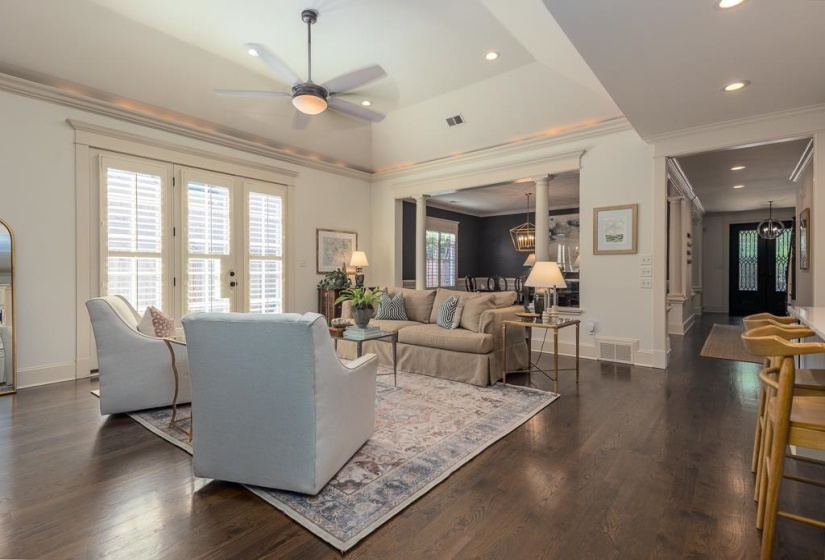 Spacious living area featuring dark wood-finish flooring, a tray ceiling with a contemporary ceiling fan, and recessed lighting