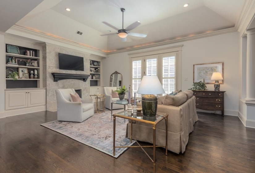 Hardwood flooring throughout featuring a tray ceiling with recessed lighting and crown molding
