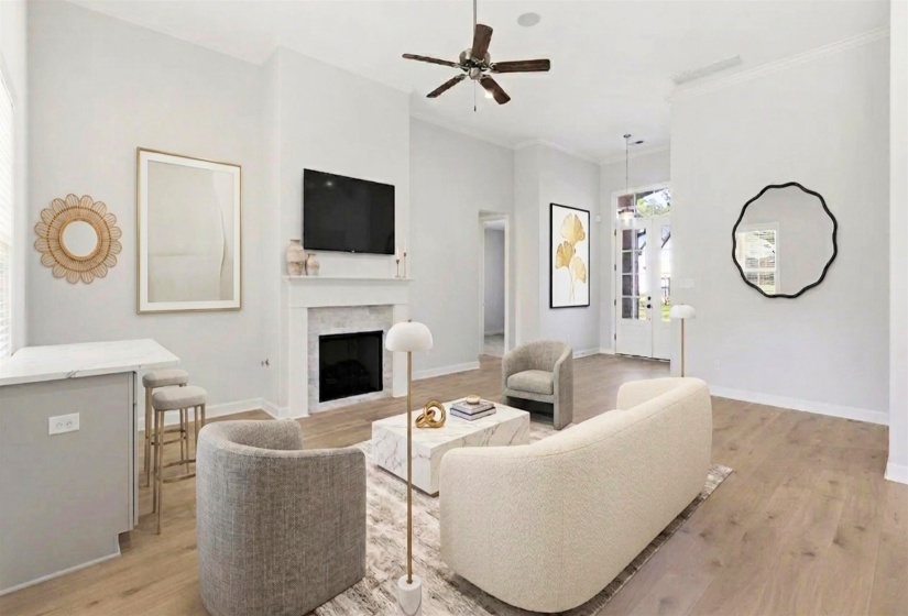 Spacious living area featuring light wood-finish flooring, a contemporary fireplace with a stone surround and white mantel, and soaring vaulted ceilings