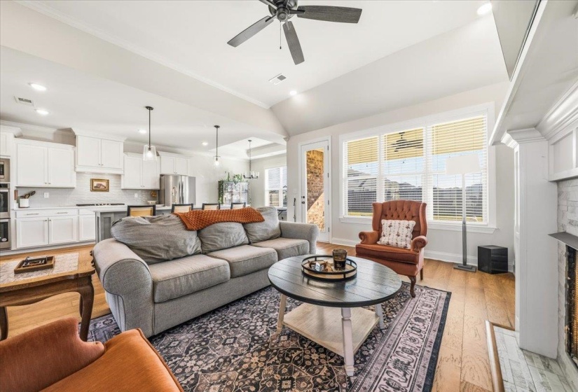 Living area with light wood-type flooring, a fireplace, ornamental molding, recessed lighting, and ceiling fan