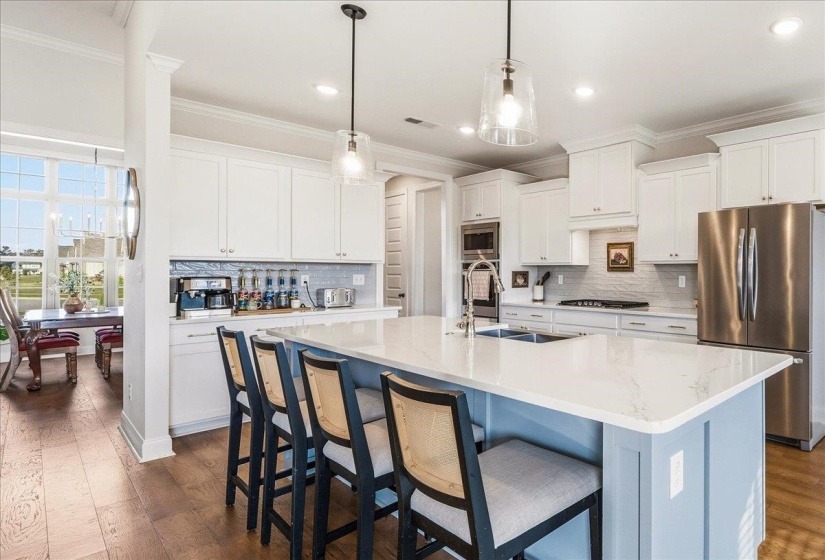Kitchen with stainless steel appliances, white cabinetry, backsplash, ornamental molding, and recessed lighting
