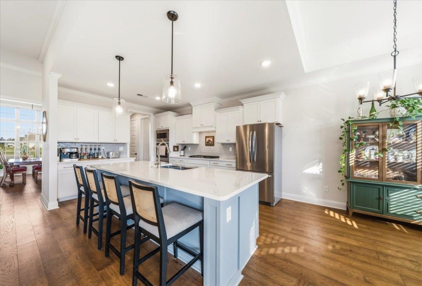 Kitchen with a kitchen breakfast bar, white cabinets, ornamental molding, stainless steel appliances, and dark wood finished floors