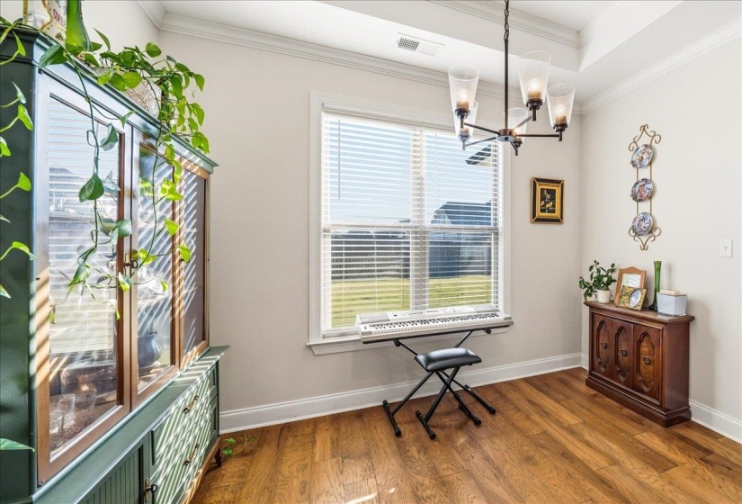 Living area with dark wood-type flooring, a chandelier, and crown molding