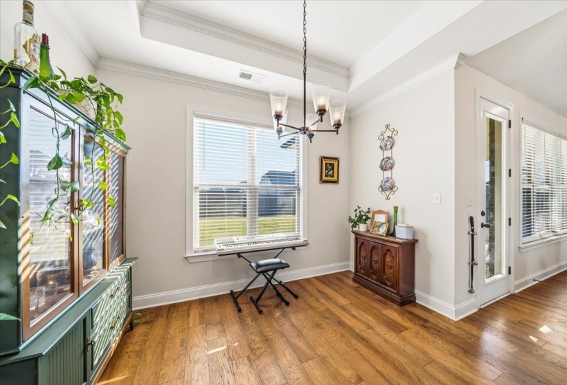 Dining room with a chandelier, wood finished floors, crown molding, and a tray ceiling