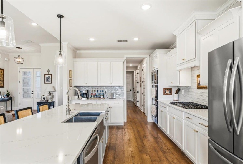 Kitchen featuring white cabinets, appliances with stainless steel finishes, hanging light fixtures, french doors, and ornamental molding