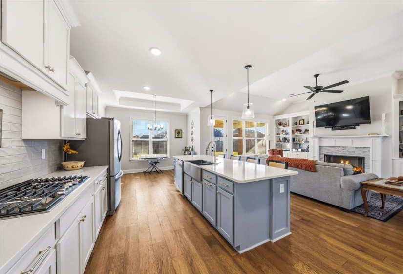 Kitchen with hanging light fixtures, dark wood-style flooring, white cabinets, appliances with stainless steel finishes, and open floor plan