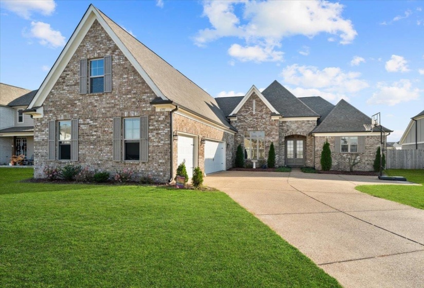 View of front of property featuring driveway, brick siding, a front lawn, and a shingled roof