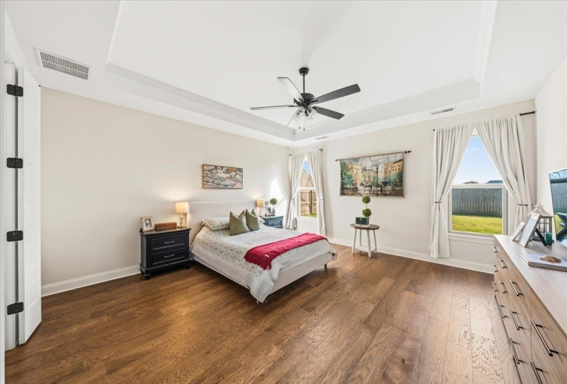 Bedroom with a tray ceiling, dark wood finished floors, and ceiling fan
