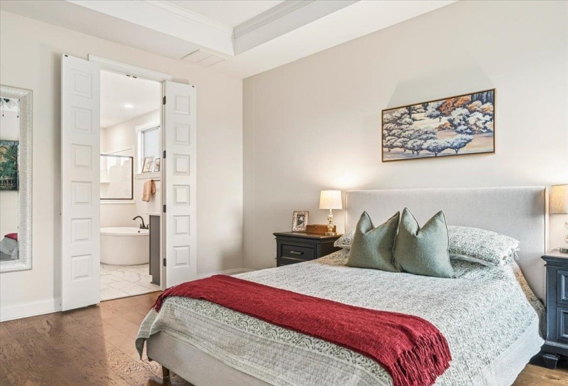 Bedroom featuring wood finished floors, crown molding, and ensuite bath