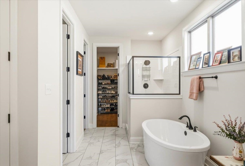 Bathroom featuring a shower stall, a soaking tub, a walk in closet, and light marble finish floors