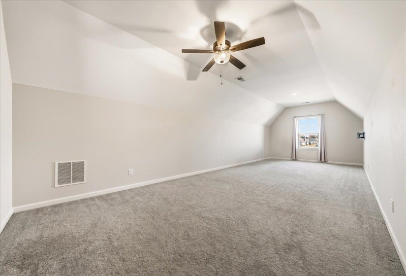 Additional living space with vaulted ceiling, carpet floors, and a ceiling fan