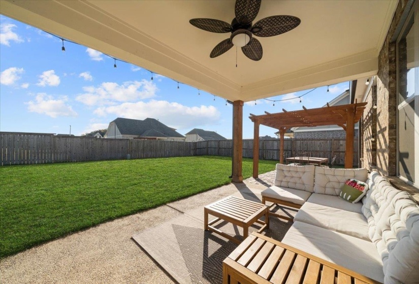 Fenced backyard with an outdoor hangout area, a patio, ceiling fan, and a pergola