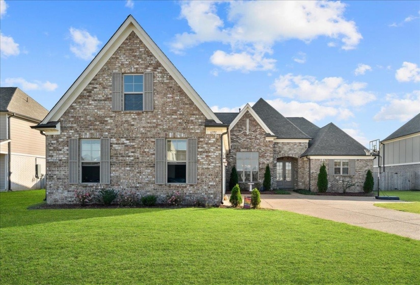 View of front facade with a front yard, brick siding, and driveway