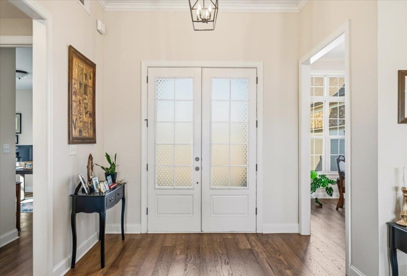 Entryway with wood finished floors, crown molding, and french doors