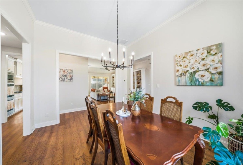 Dining space featuring dark wood-style floors, crown molding, and a chandelier