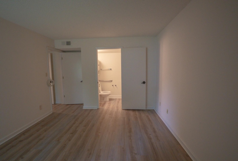 Spacious interior room featuring wood-finish flooring and light-toned wall finishes