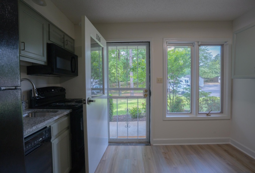 Compact kitchen with granite-look countertops, light-colored cabinetry, and black appliances including a refrigerator, range, microwave, and dishwasher