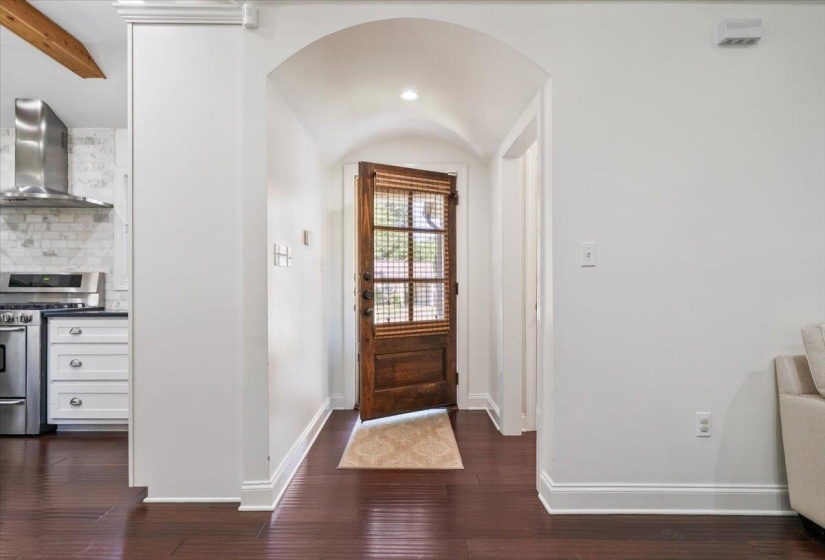Arched entryway featuring a dark wood door with glass paneling, recessed lighting, and rich wood-finish flooring