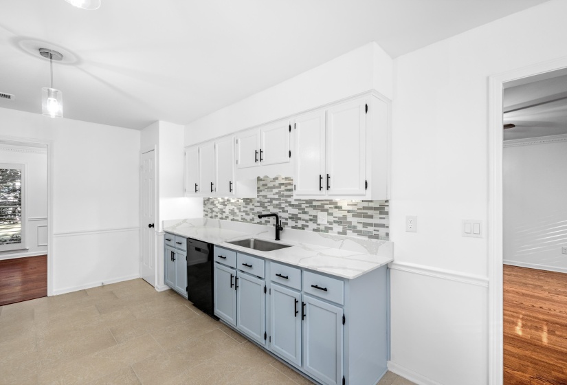 Kitchen featuring two-tone cabinetry, a tile backsplash, and a black appliance suite