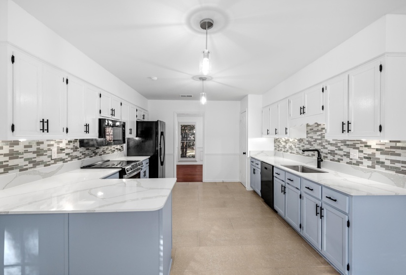 Open-concept kitchen featuring two-tone cabinetry, stone-finish countertops, a mosaic tile backsplash, and stainless steel appliances