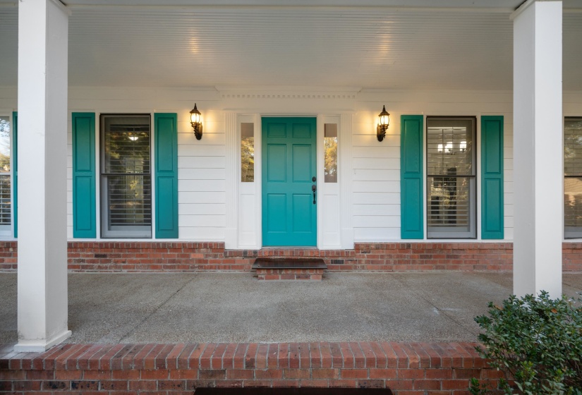Inviting front porch featuring a vibrant teal entry door, flanking sidelights, and twin exterior sconces