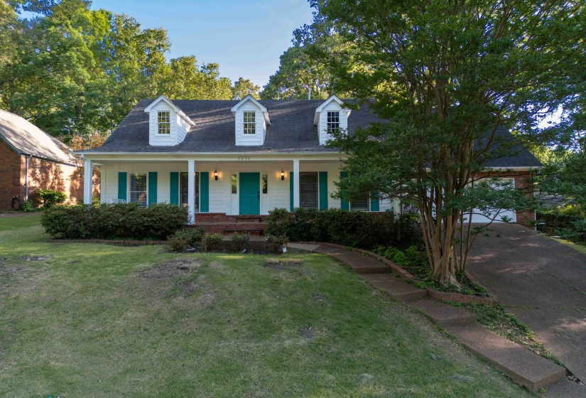 White exterior residence with a covered front porch, dormer windows, turquoise shutters, and a matching front door