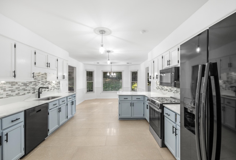 Modern kitchen featuring two-tone cabinetry with matte black hardware, white countertops, and a mosaic tile backsplash